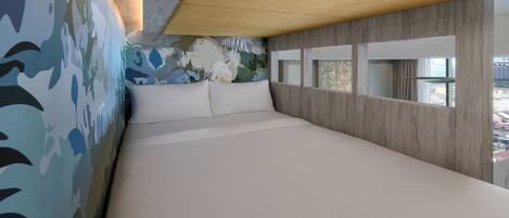 A modern bedroom with a large bed, a wooden ceiling, and a city view through a window.