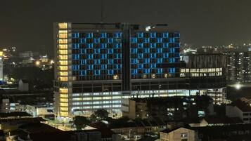 Un edificio de gran altura con varios pisos, que presenta un diseño arquitectónico moderno y ventanas iluminadas.