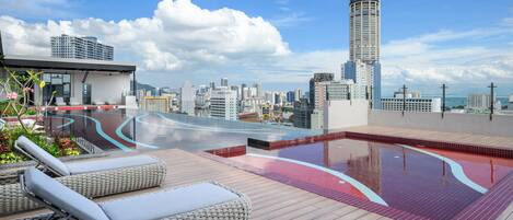 Un espace piscine sur le toit, avec des chaises longues et une vue panoramique sur la ville.