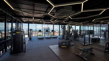A gym with exercise equipment, large windows, and a city view.
