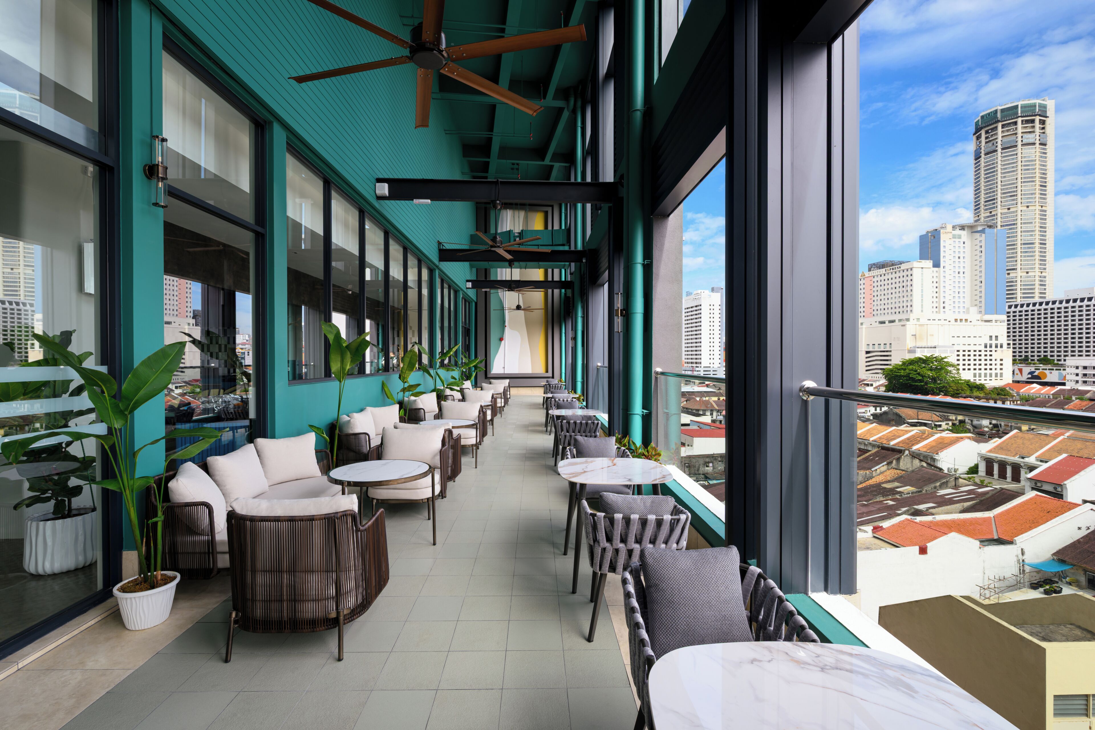 A modern indoor balcony with seating and potted plants, overlooking a cityscape.
