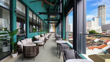 A modern indoor balcony with seating and potted plants, overlooking a cityscape.