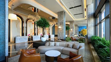 A modern lobby with a reception desk, seating area, and large windows.