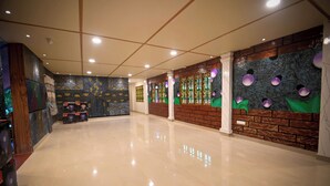 A spacious lobby with a polished floor, decorative wall murals, and a brick accent wall. - Benzy Palace Resort (Bhatkal)