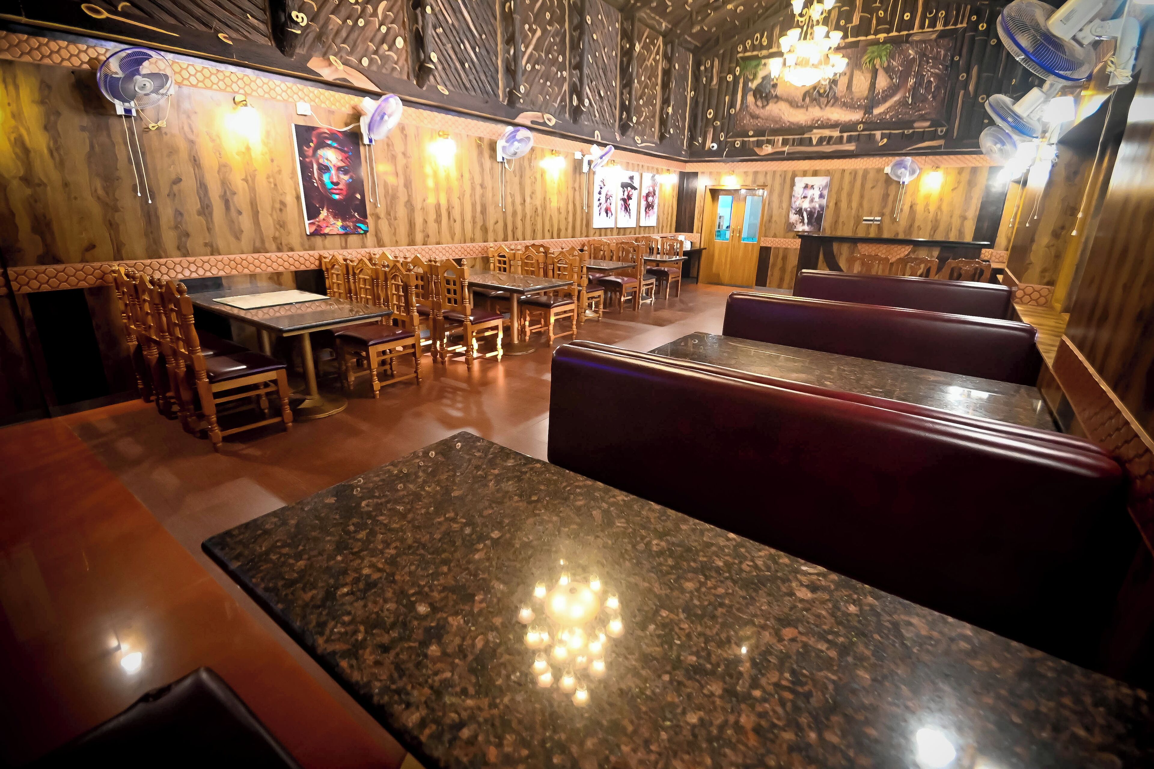 Interior de restaurante con paredes de madera, varias mesas y cabinas, y ventiladores de techo.