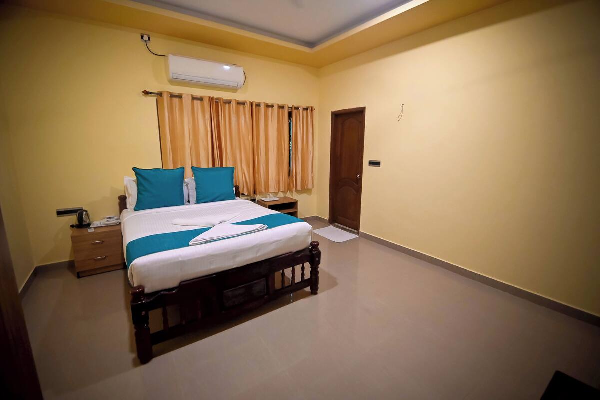 A neatly arranged bedroom with a bed, bedside table, and an air conditioning unit.