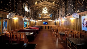 A restaurant with wooden walls and ceiling, multiple seating areas, and a chandelier. - Benzy Palace Resort (Bhatkal)