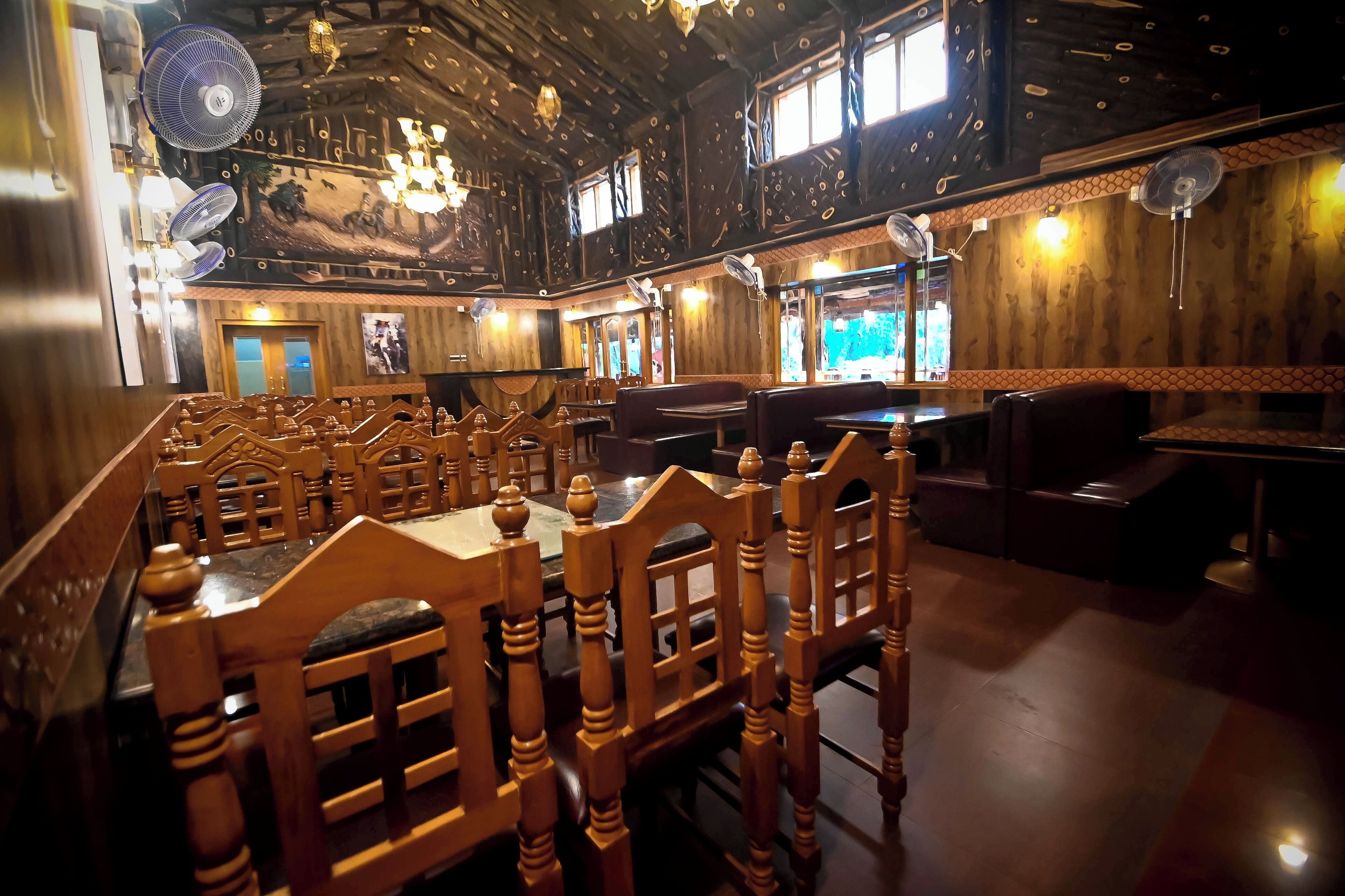 A restaurant with wooden booths and tables, ceiling fans, and a mural on the wall.