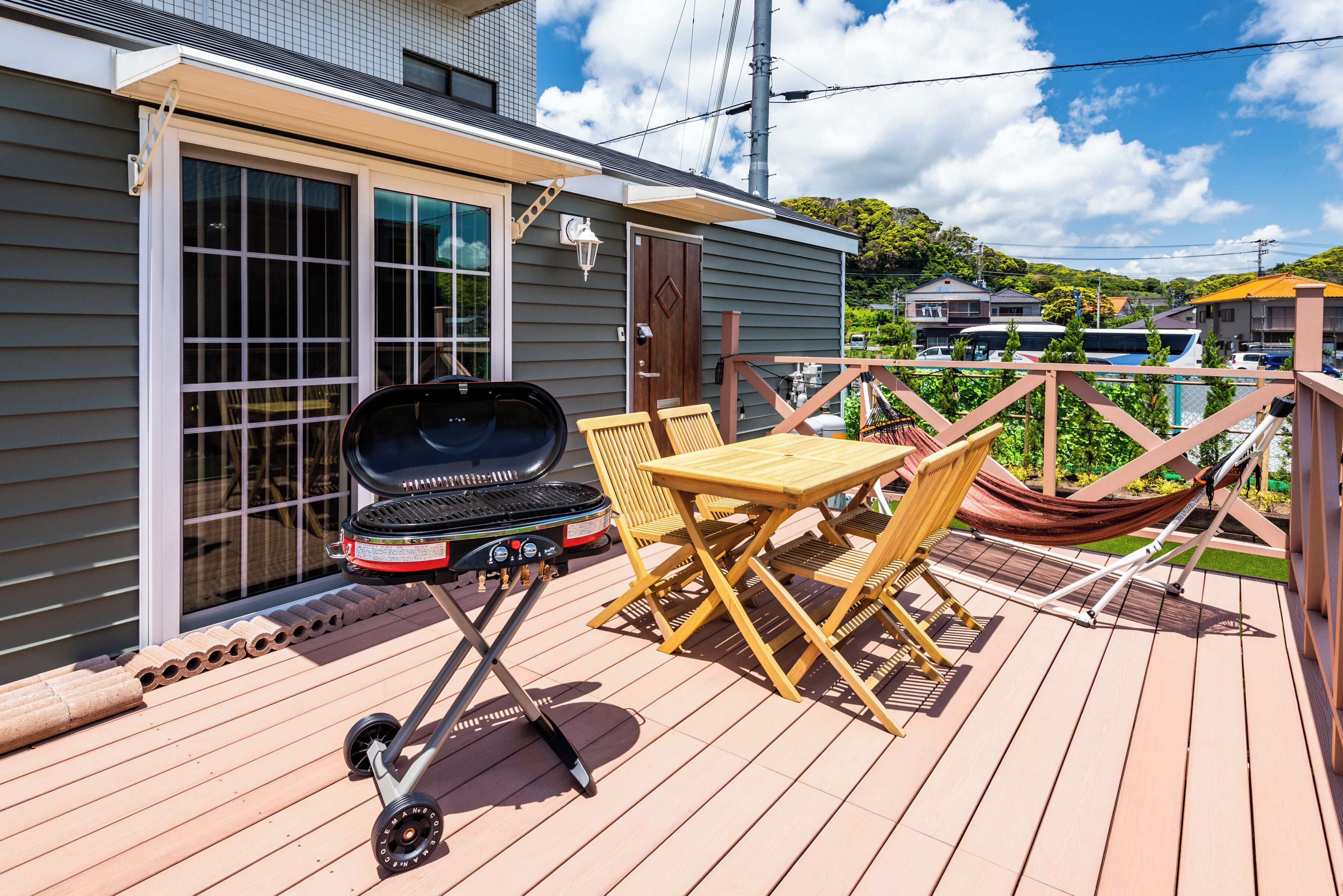 A deck with a grill, outdoor furniture, and a hammock.