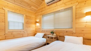 A cabin with two beds, wooden walls, a small table with a lamp, and a window with blinds. - Solana Kamogawa (Kamogawa)