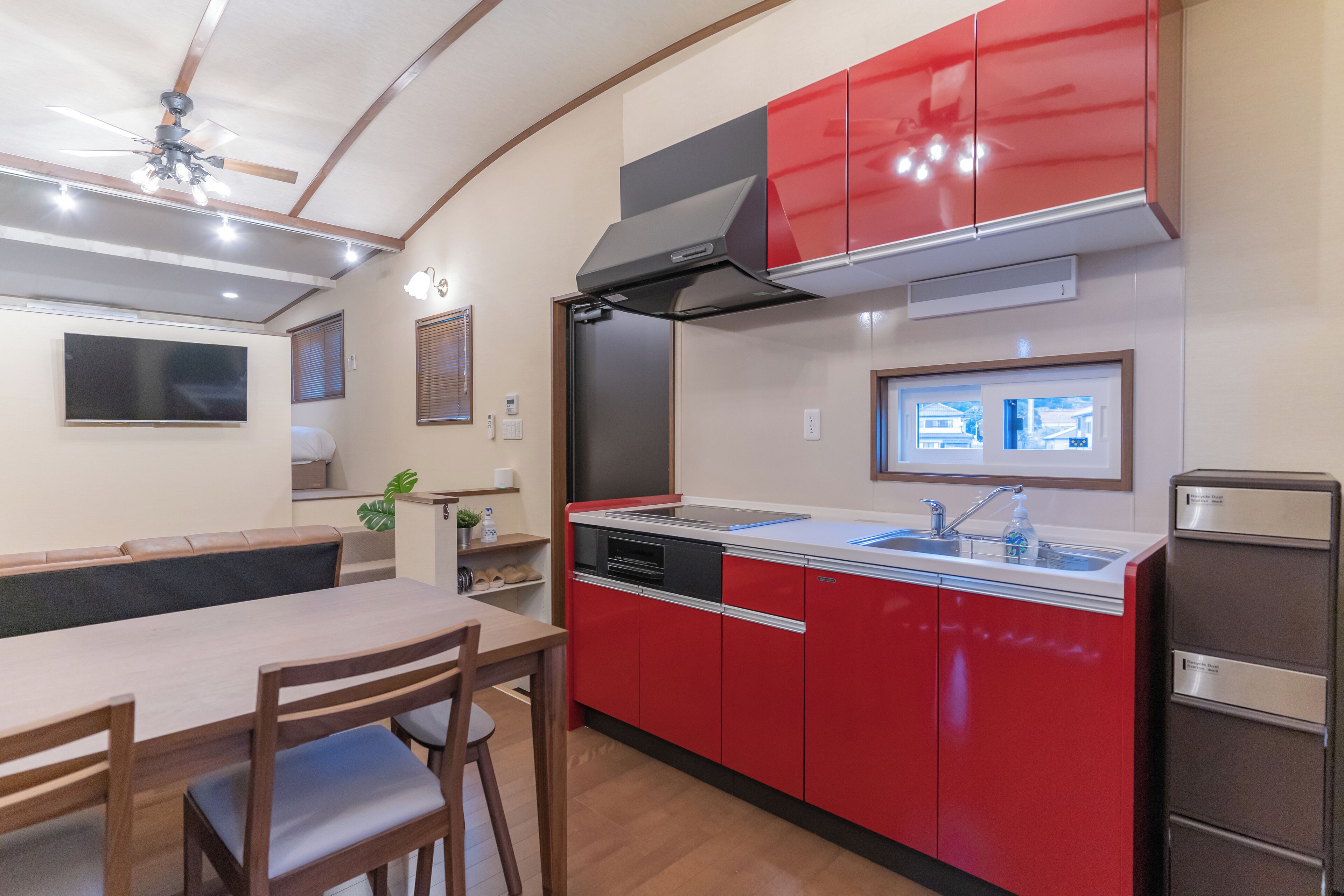 A compact kitchen with red cabinets, a built-in oven, and a sink.
