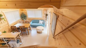 A wooden interior with a dining area, sofa, and staircase. - Solana Kamogawa (Kamogawa)