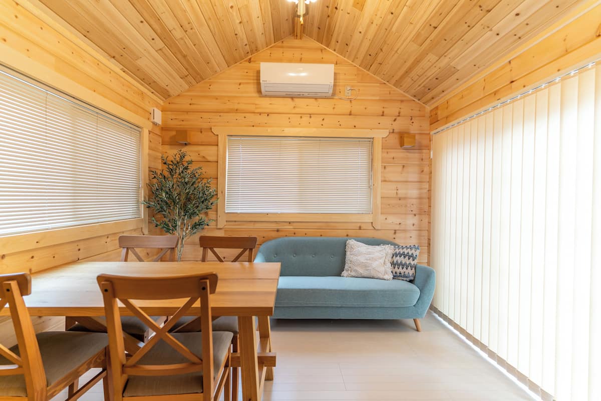 Interior de madera con una mesa de comedor, sillas, un sofá y un aire acondicionado instalado en el techo.