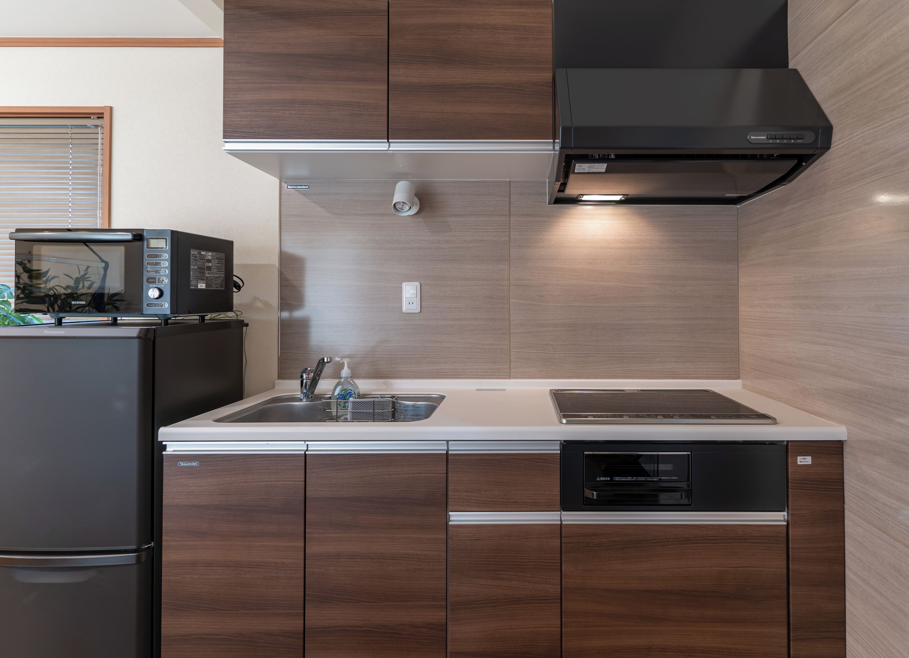 A kitchen with a microwave, sink, dishwasher, and wooden cabinets.