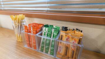 A clear plastic storage organizer with compartments containing various tea and coffee packets.