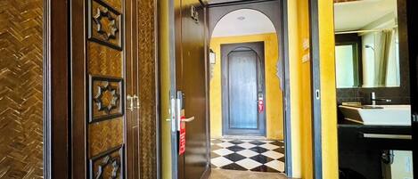 Un pasillo con piso a cuadros que conduce a una puerta con la inscripción 'DA'.