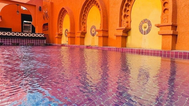 A courtyard with a tiled pool and a building with arches and a tiled facade. - Le Bush (Pattaya)
