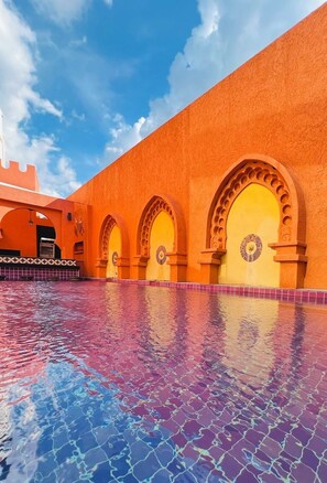 A courtyard with a tiled pool and a building with arches and a tiled facade. - Le Bush (Pattaya)