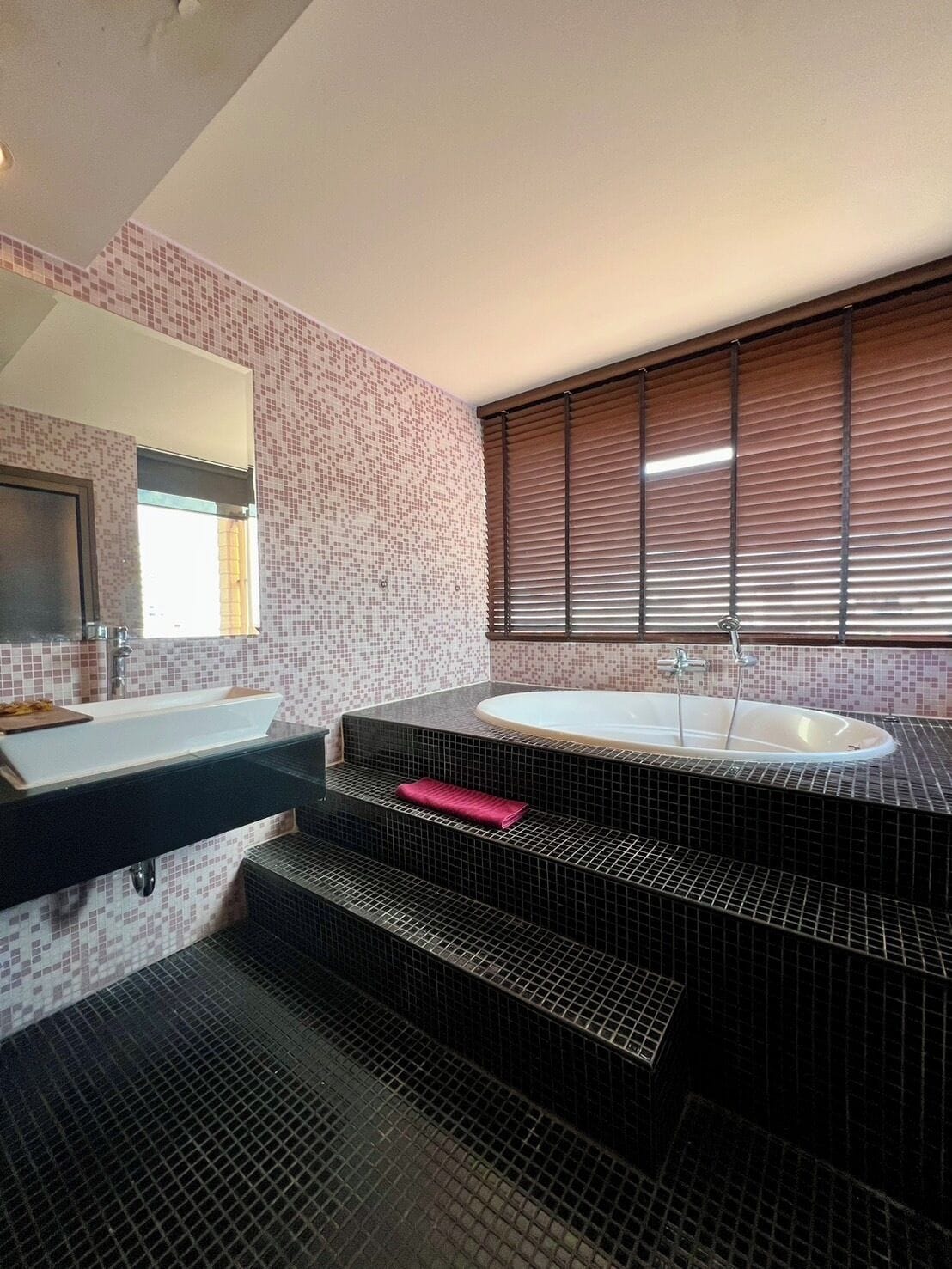Une salle de bain moderne avec une grande baignoire, deux lavabos et un miroir.