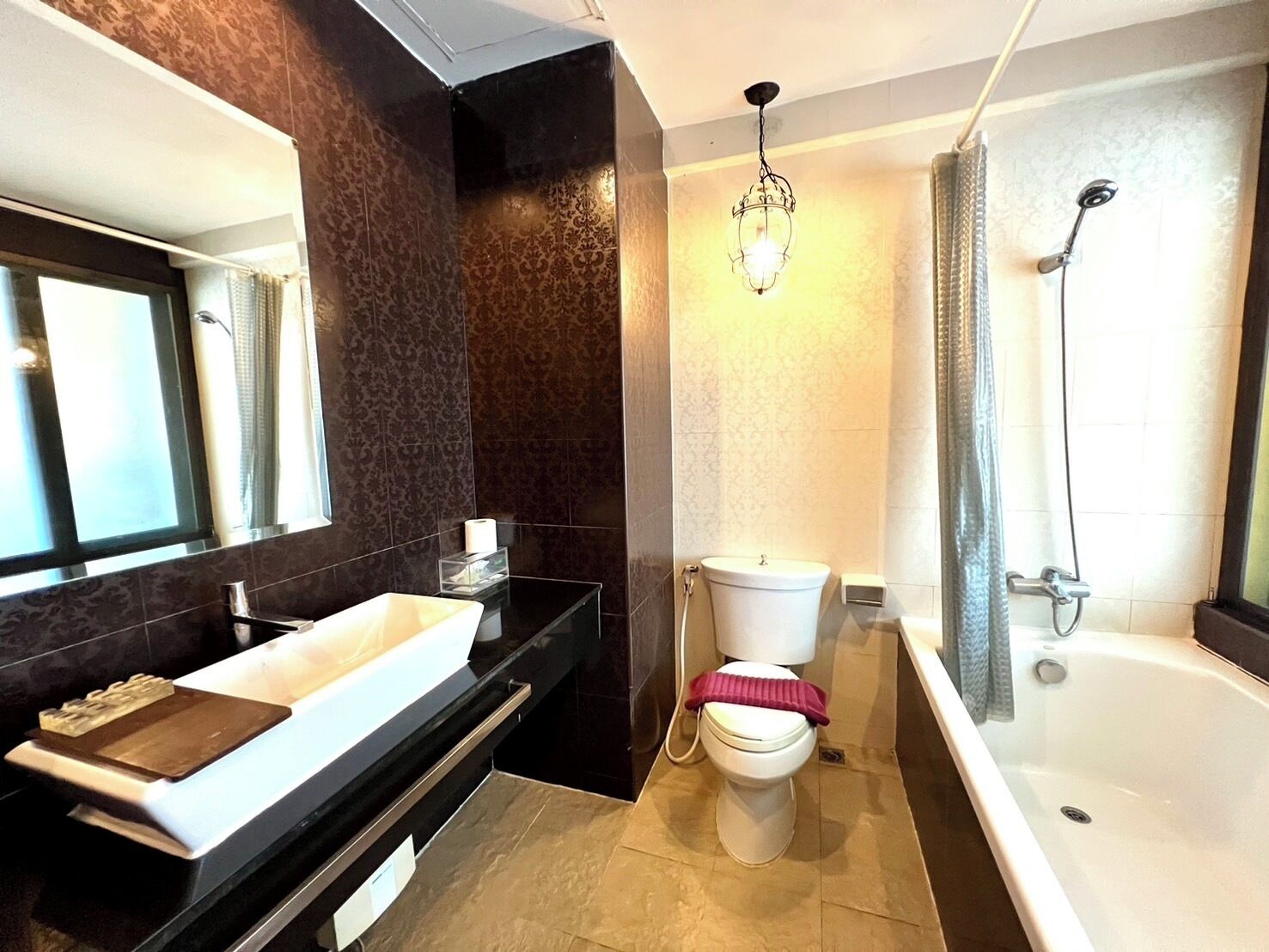 Une salle de bain moderne avec un plan de toilette noir, un lavabo blanc et une baignoire.