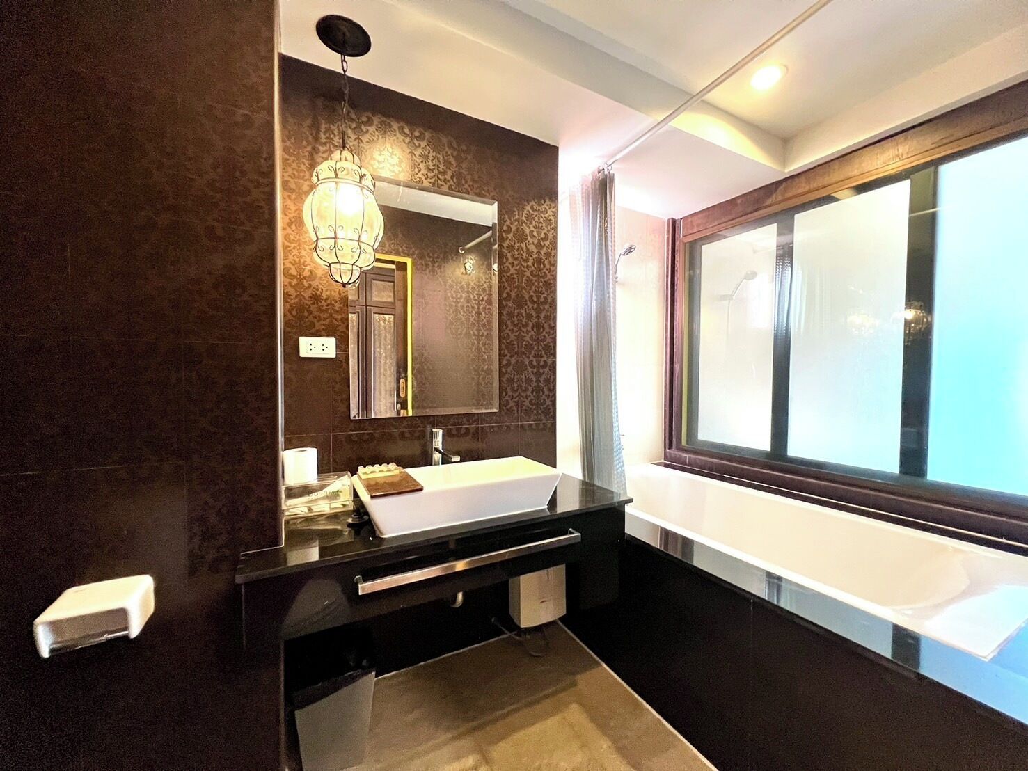 A modern bathroom with a large mirror, a white sink, and a vanity with a towel rack.