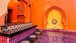 A courtyard with a tiled floor, a fountain, and a seating area with stools. - Le Bush (Pattaya)