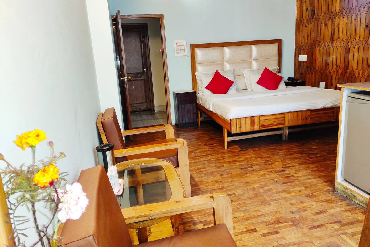 Un dormitorio con una cama de madera, una silla de madera, una mesita pequeña y un armario de madera.
