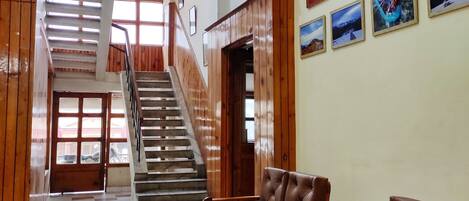 A lobby with a staircase, wooden benches, a reception desk, and framed pictures on the wall.