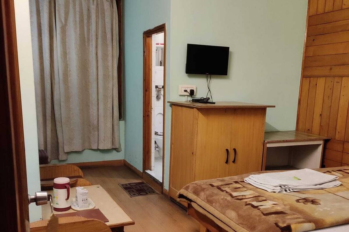 Una habitación pequeña y acogedora con cama, escritorio, silla, televisor y armario.
