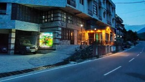 A multi-story building with a ground-floor restaurant, a visible staircase, and a parked vehicle. - HimalayanHamlet ValleyView (Kullu)