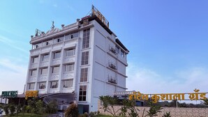 A multi-story hotel with a white facade and a signboard in a foreign language. - Hotel Kushala Grand, Dombivali (Ambernath)