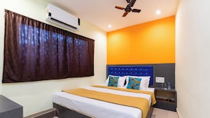 A hotel room with a bed, a nightstand, an air conditioner, and a ceiling fan. - Hotel Shera Residency (Mumbai)