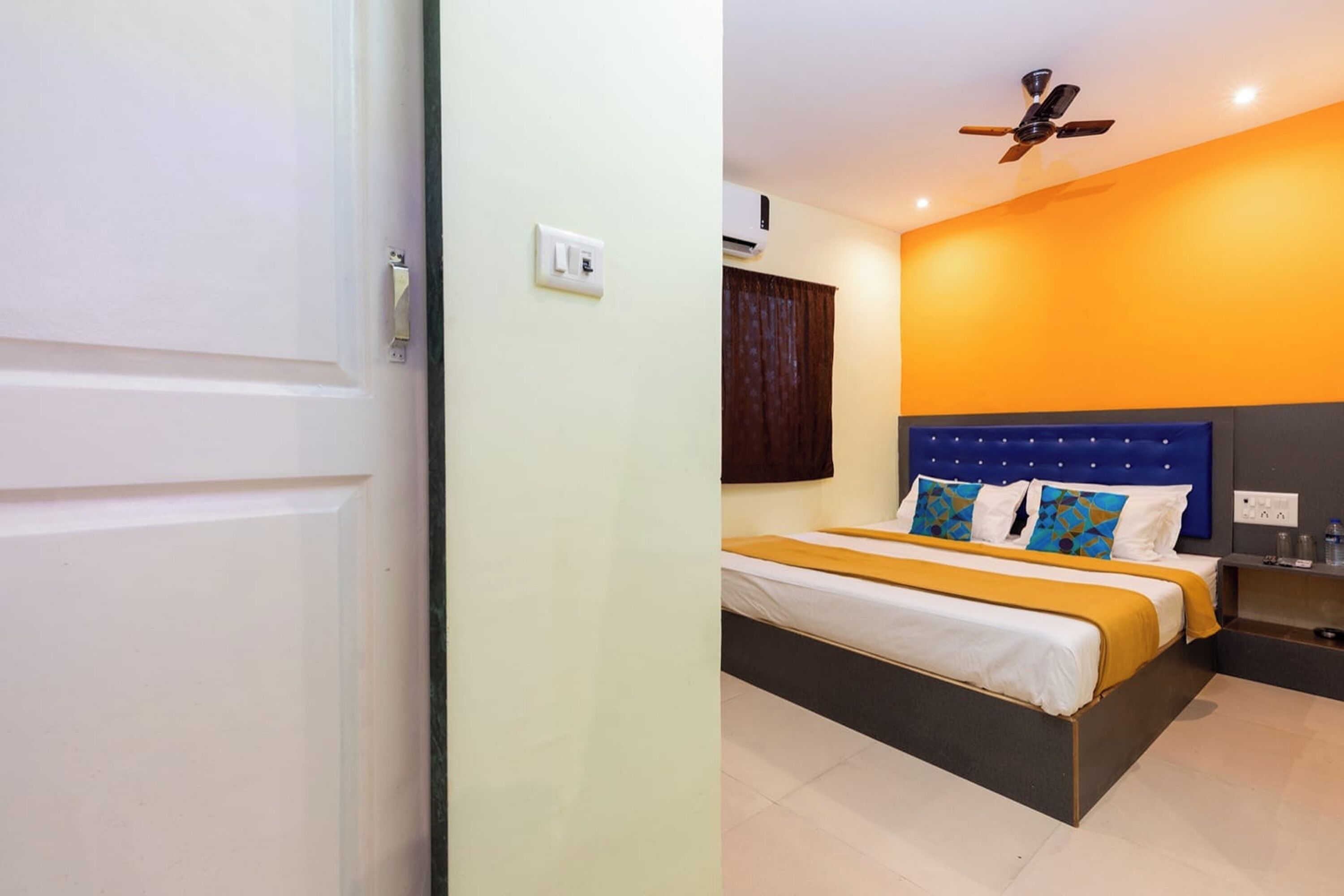 A bedroom with a bed, a ceiling fan, an air conditioning unit, and a nightstand.