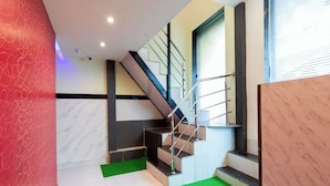 A modern interior with a staircase, green carpet, and a marble wall. - Hotel Shera Residency (Mumbai)