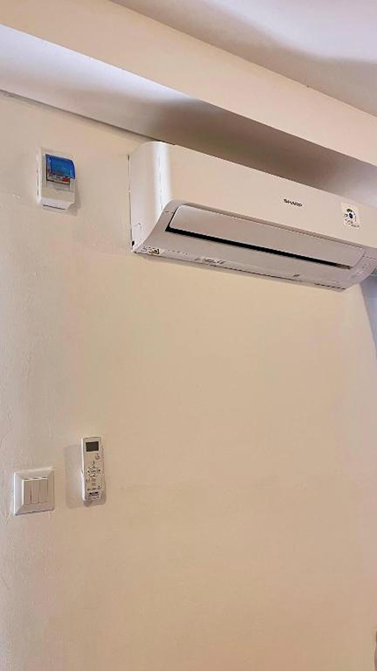 Eine wandmontierte Klimaanlage mit Fernbedienung und Wandtaster.