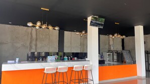 A bar area with a counter, stools, and a menu board.