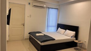 A modern bedroom with a black bed frame, white bedding, and a small bedside table.