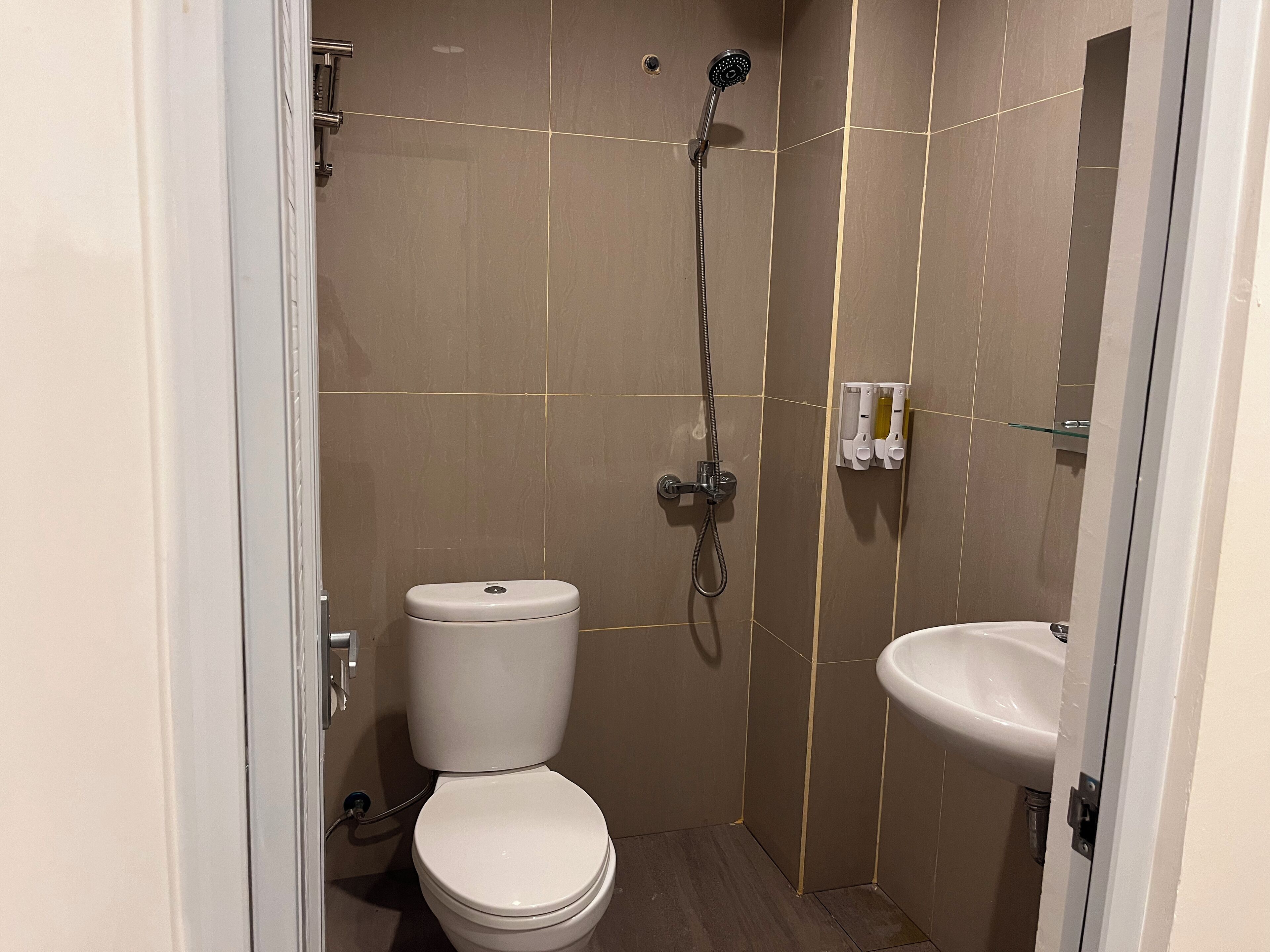 Une petite salle de bain moderne équipée de toilettes, d’une douche et d’un lavabo.