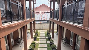 A covered outdoor area with a central pathway, potted plants, and seating arrangements.