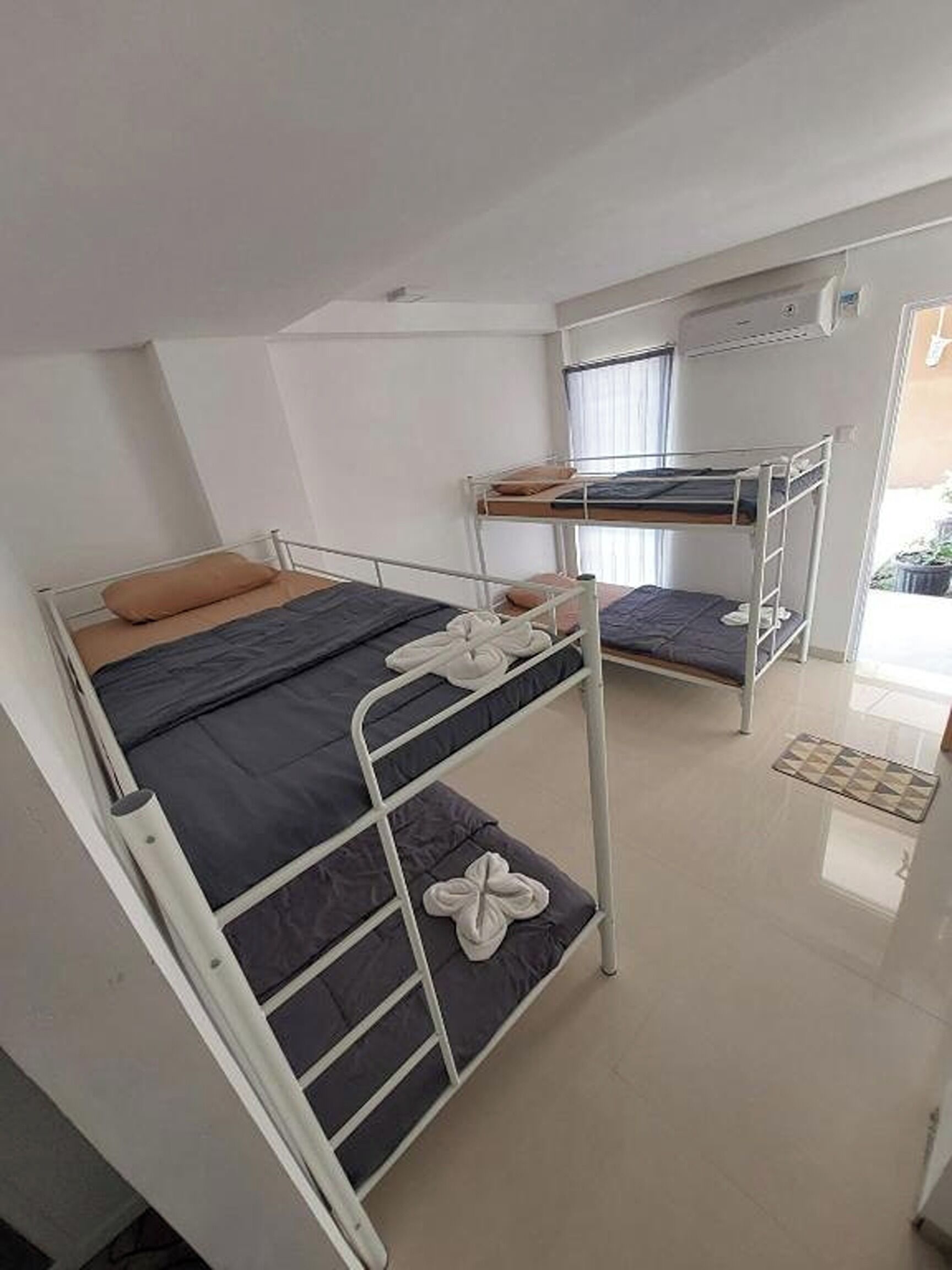 A dormitory room with bunk beds, a small table, and a window.