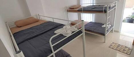 A dormitory room with bunk beds, a small table, and a window.
