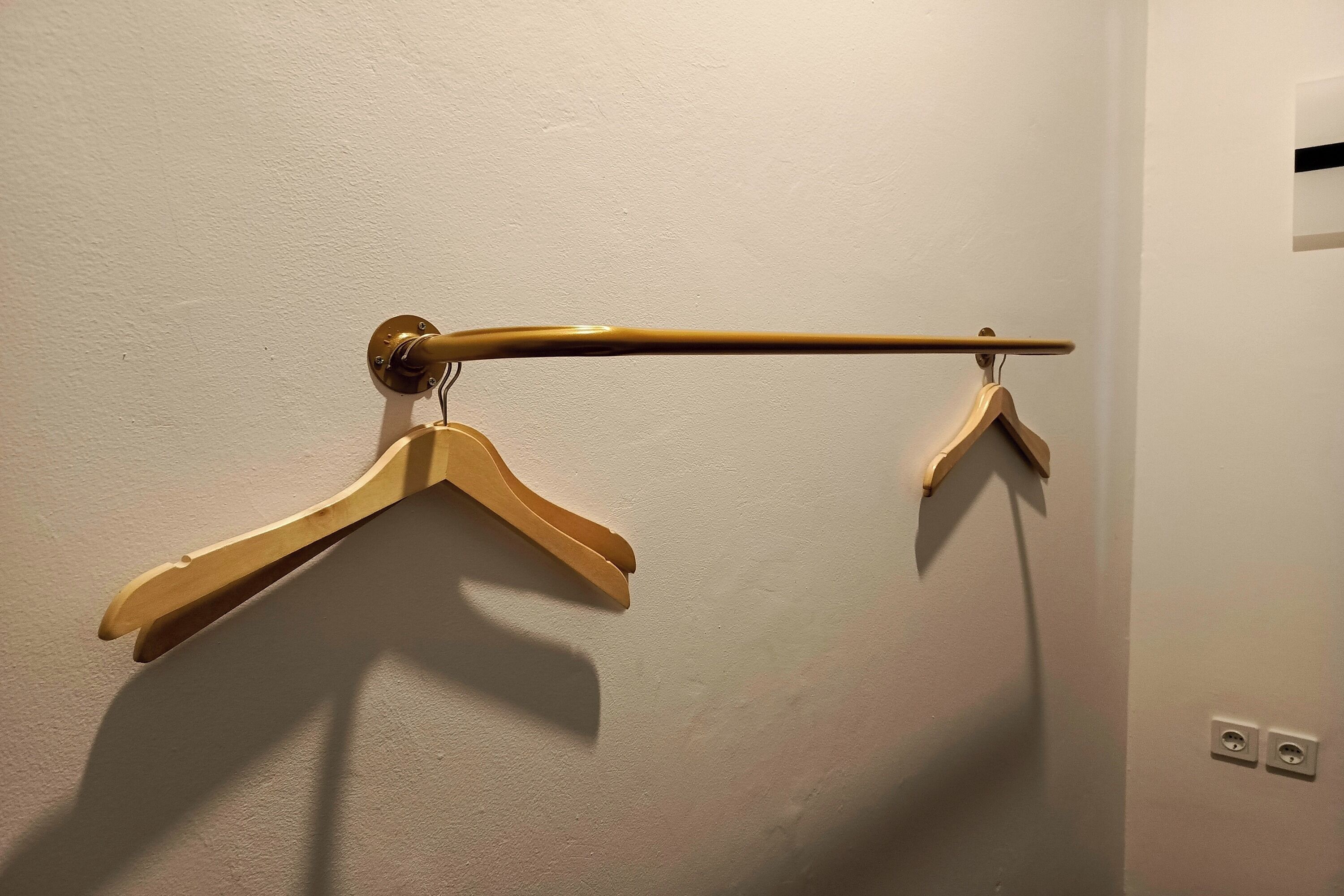 A wall-mounted wooden hanger with two hangers.