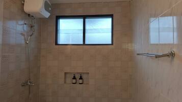 Una ducha con ventana, un perchero y dos botellas en la pared.