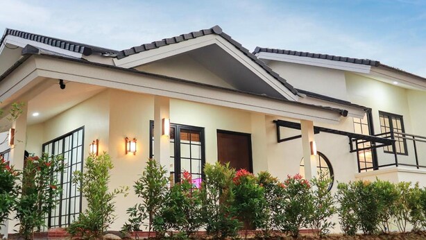 A modern two-story house with a covered porch, large windows, and a tiled roof.