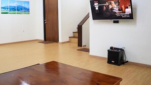 A living room with a wooden coffee table, a TV mounted on the wall, and a staircase leading to another floor.