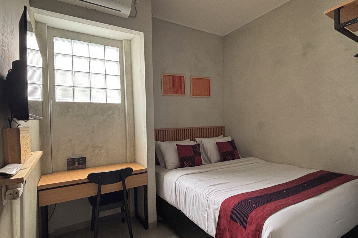 Une chambre à coucher avec un lit, un bureau, une chaise et une fenêtre.