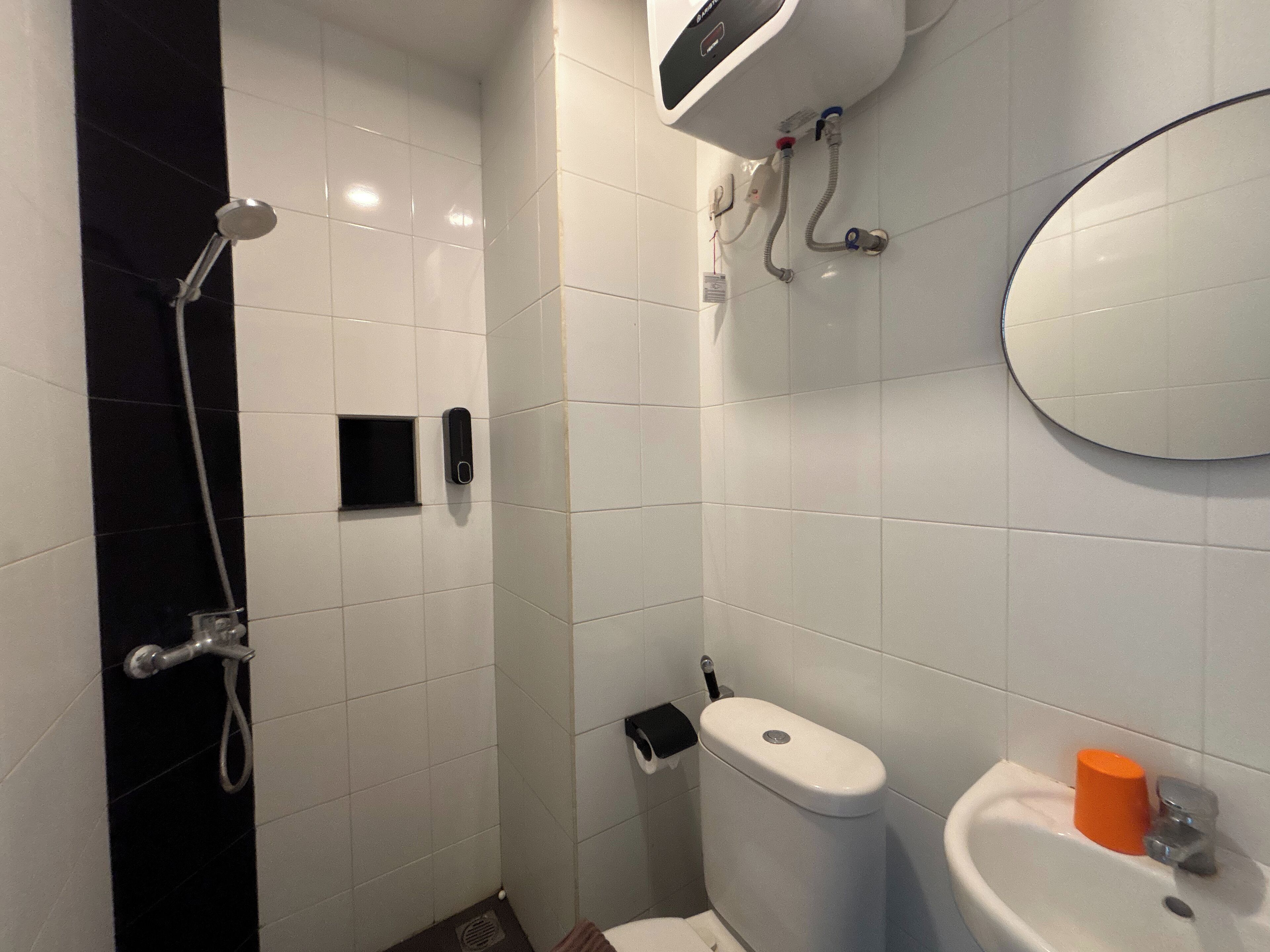 A bathroom with a shower, toilet, sink, and a mirror.