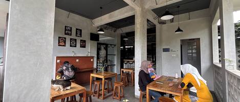 Un café con mesas y sillas de madera, una barra y algunos objetos decorativos en las paredes.