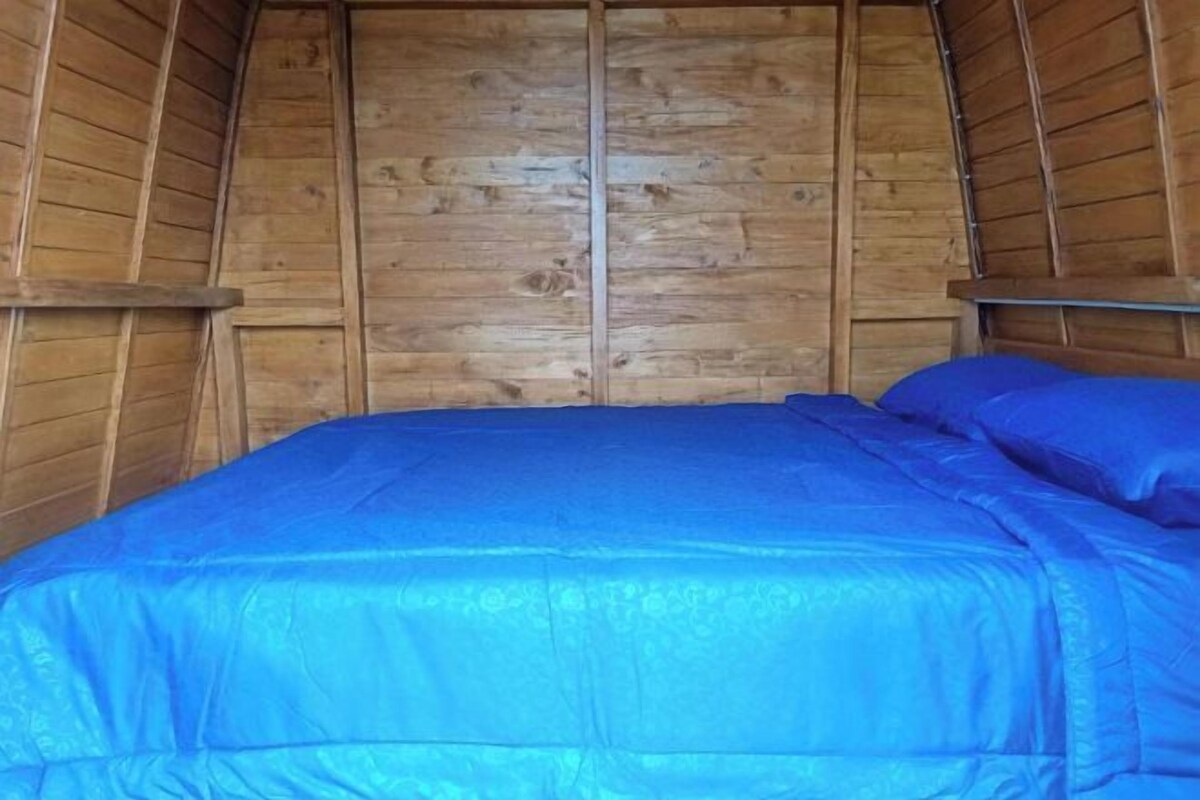 Een houten interieur met een bed met blauw beddengoed.