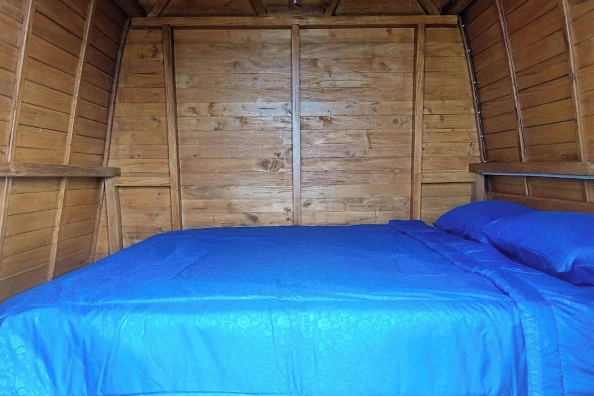 Een kamer met houten vloer, een bed en een houten deur.